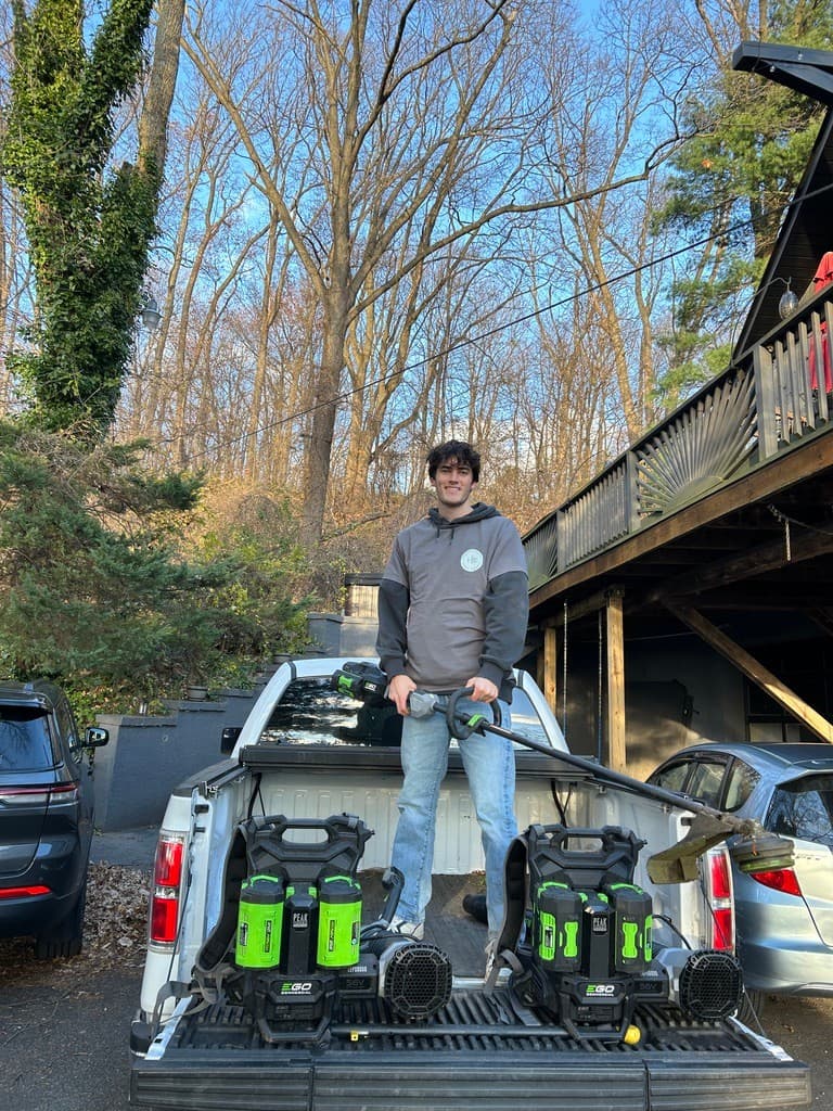 Shanin standing in the bed of a work truck with trimmer and battery packs